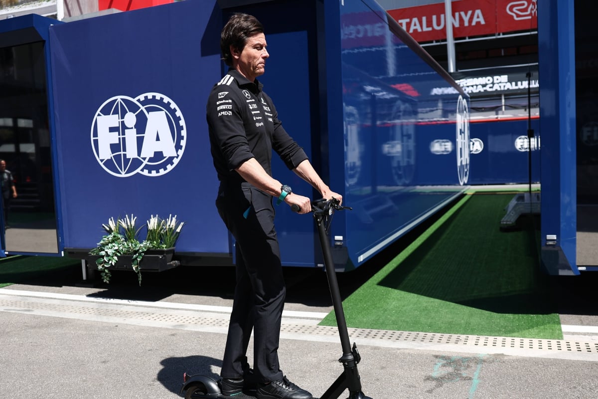 Toto Wolff scoots past the FIA badge in the F1 paddock