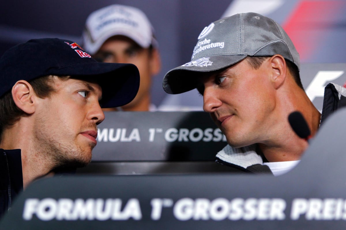 An image of German F1 legends Sebastian Vettel and Michael Schumacher in conversation at a press conference