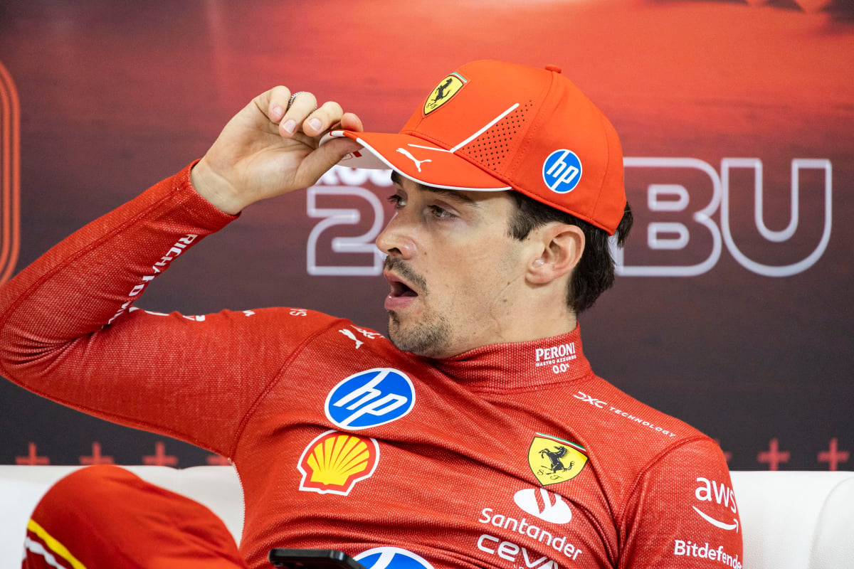 Charles Leclerc yawns at an F1 press conference wearing Ferrari gear