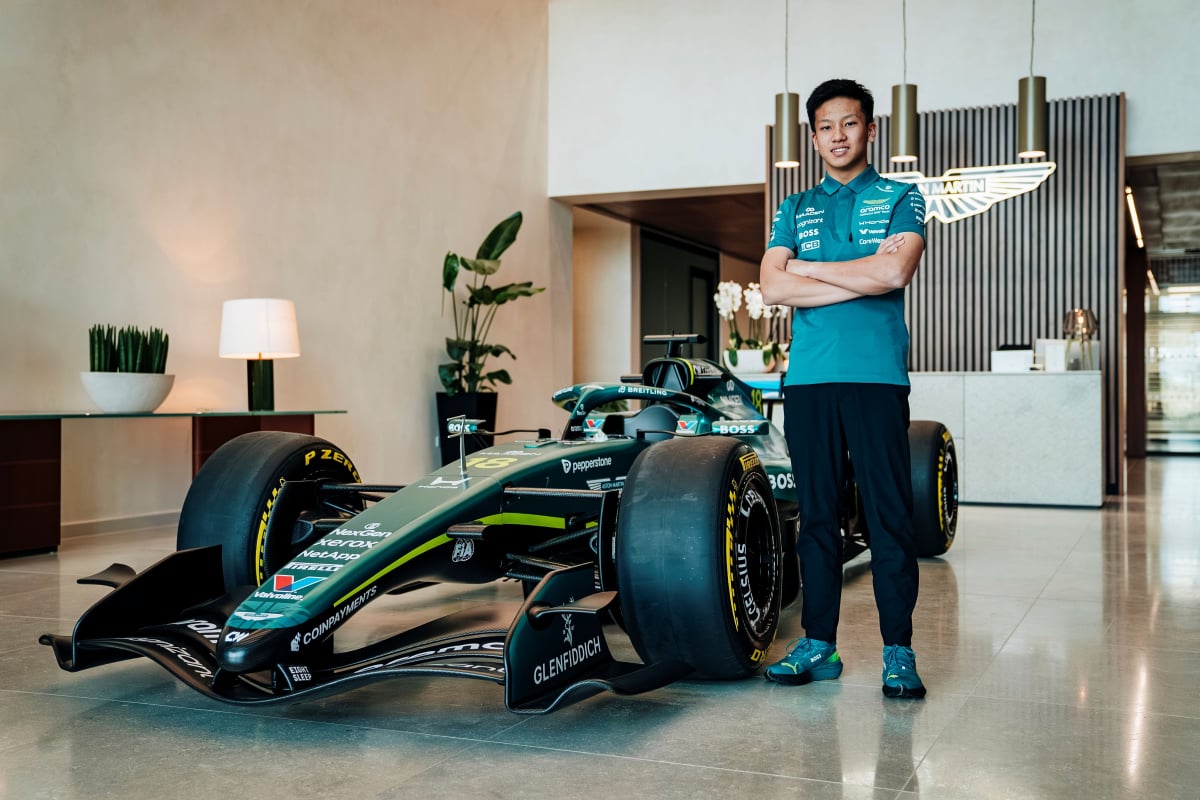 Zhenrui Chi stands beside an Aston Martin F1 car