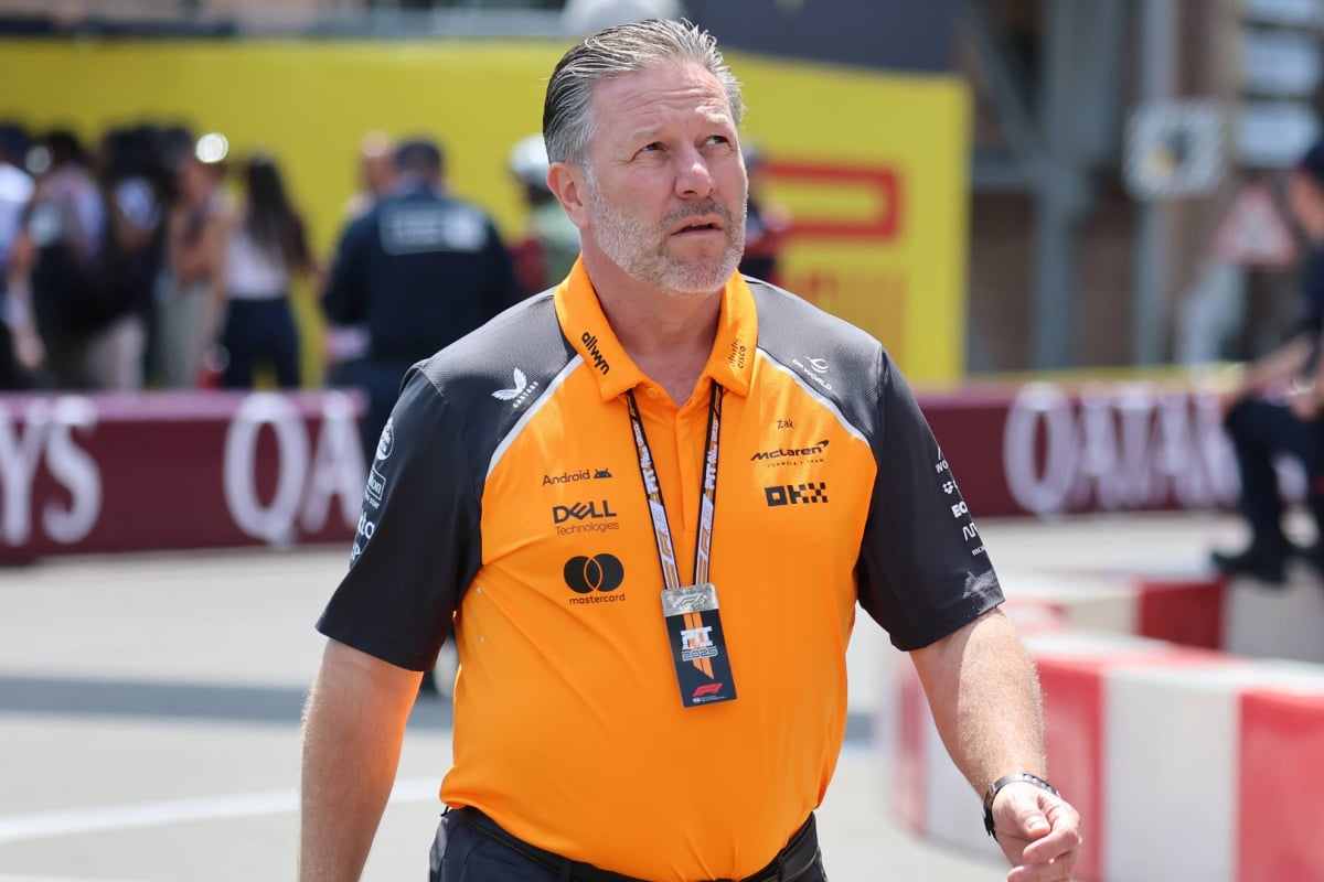 McLaren CEO in papaya McLaren F1 t-shirt and black trousers walking through the F1 paddock with a serious expression