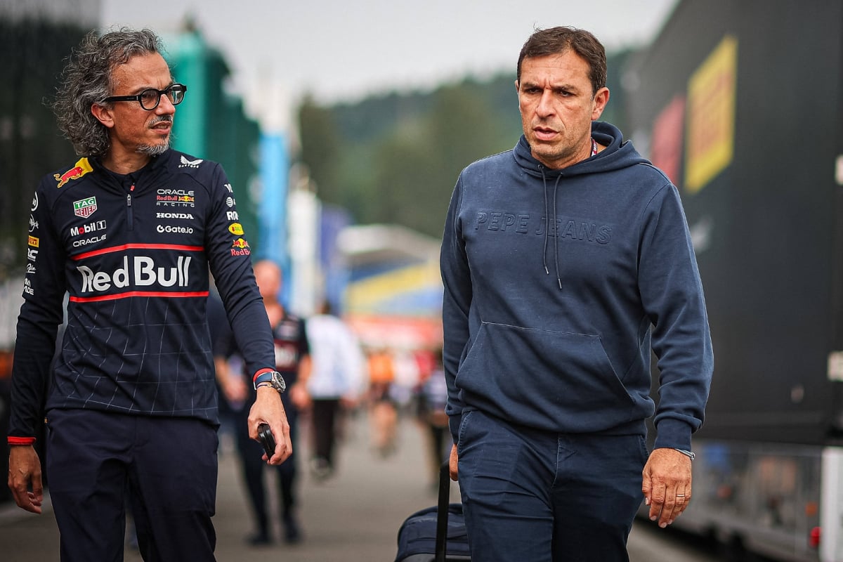 Mekies in Red Bull F1 kit with Wache in tracksuit walking through F1 paddock