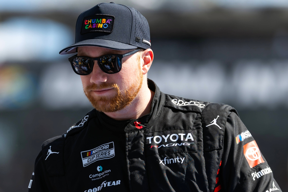 An image of 23xi NASCAR star Tyler Reddick low-fiving the crowd ahead of a race