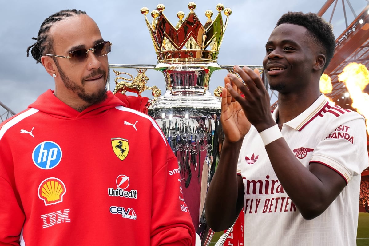 Lewis Hamilton looks over at a clapping Bukayo Saka in front of the Emirates Stadium with the Premier League trophy between them both
