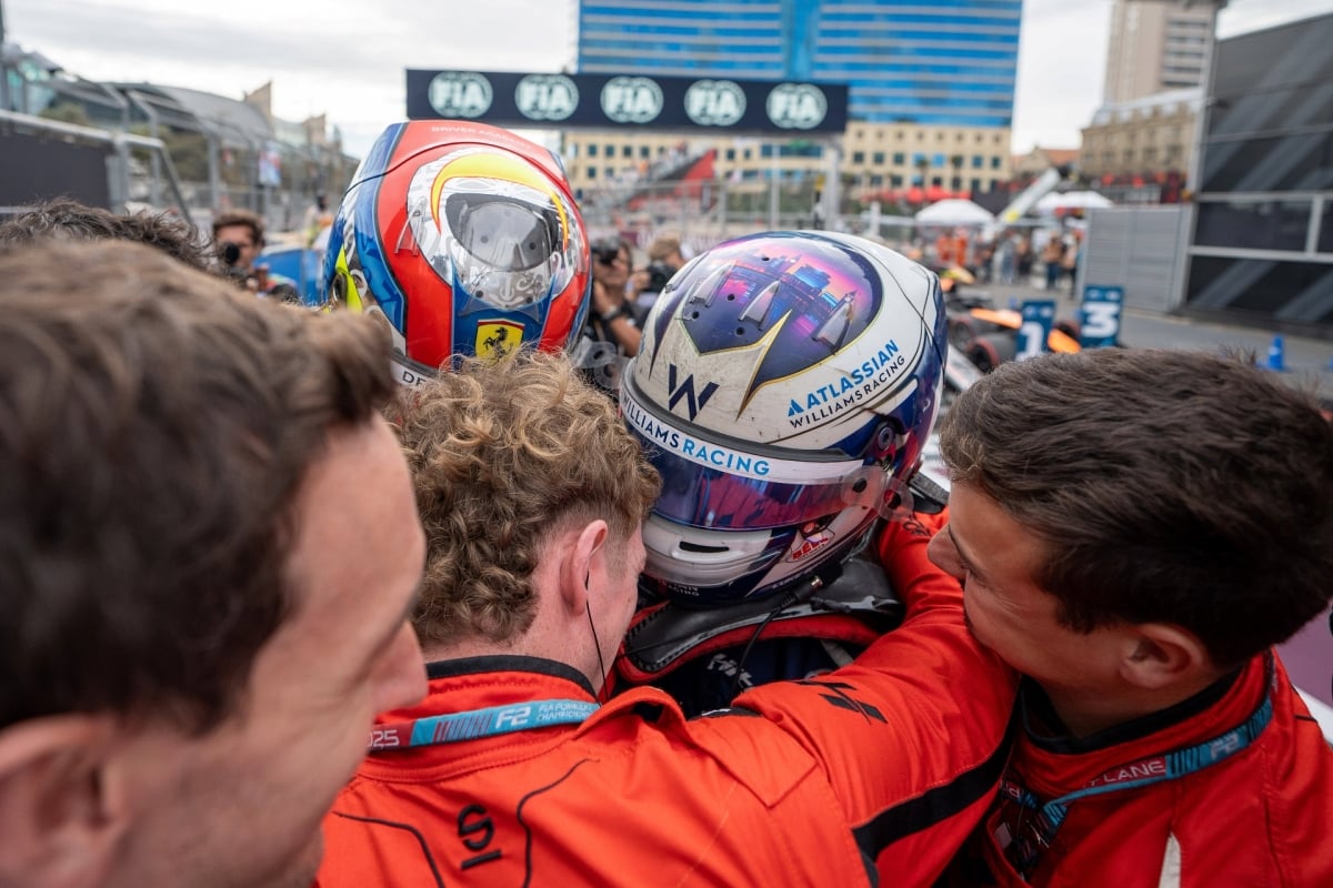Williams junior Luke Browning wearing his race helmet and celebrating with his team after a race