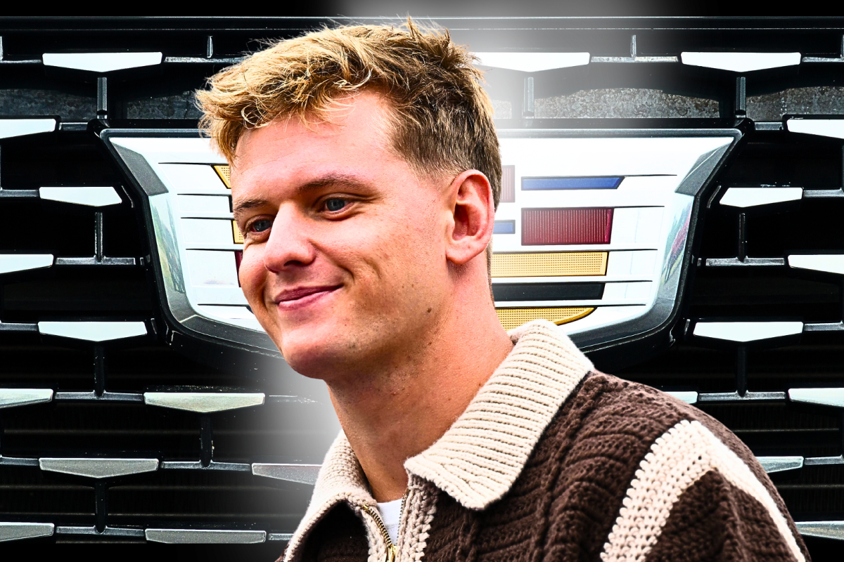 Mick Schumacher in front of a Cadillac logo looking happy