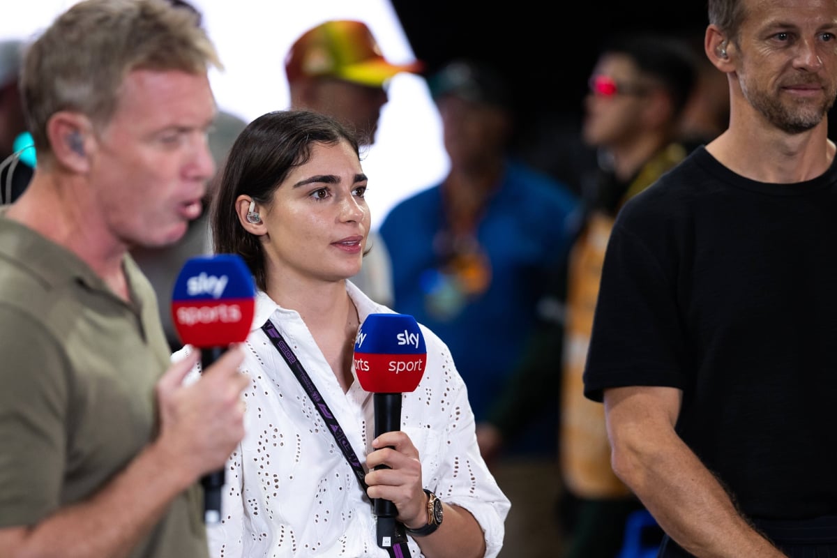 Jamie Chadwick on air with Sky Sports holding a mic stood between Simon Lazenby and Jenson Button who are out of focus