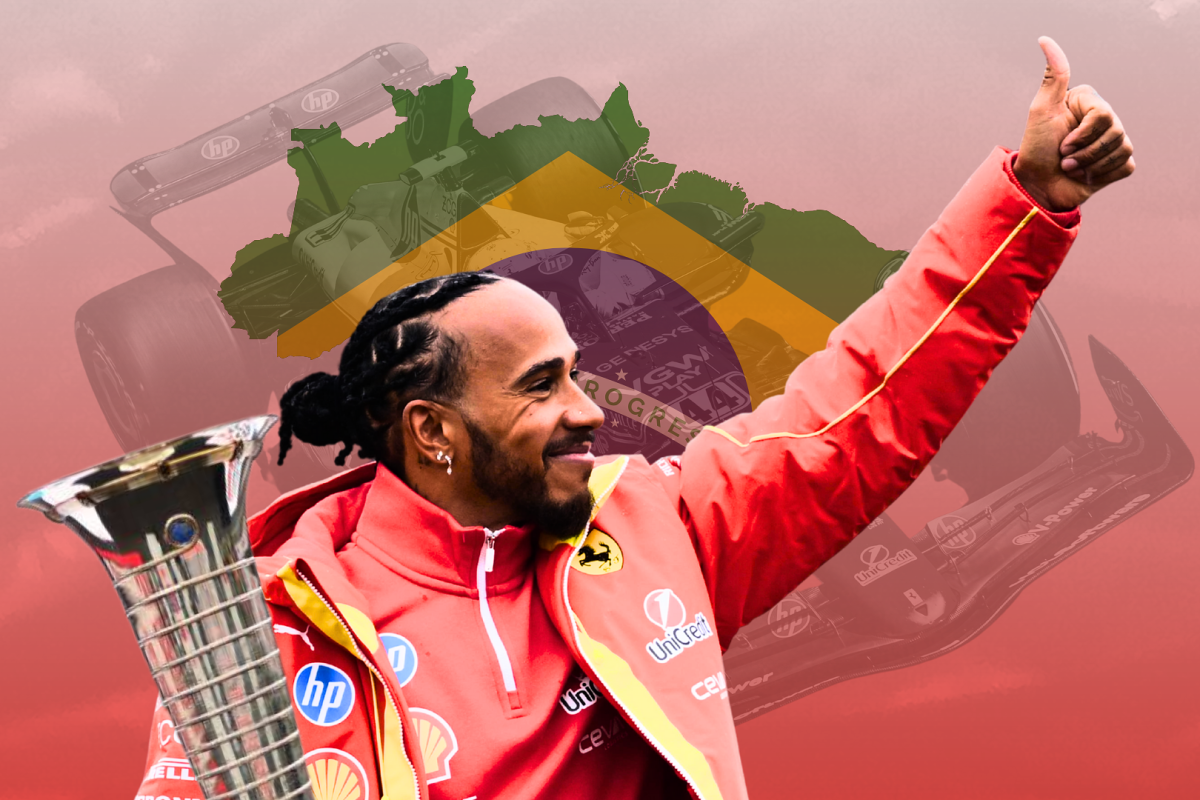 Lewis Hamilton waves and smiles as he holds a trophy with the brazil flag in the background