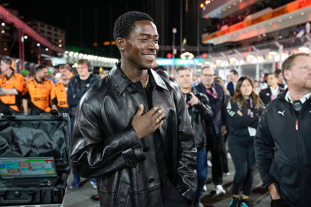 Damson Idris in sleek all black outfit with hand his hand on his chest on the F1 Las Vegas GP grid