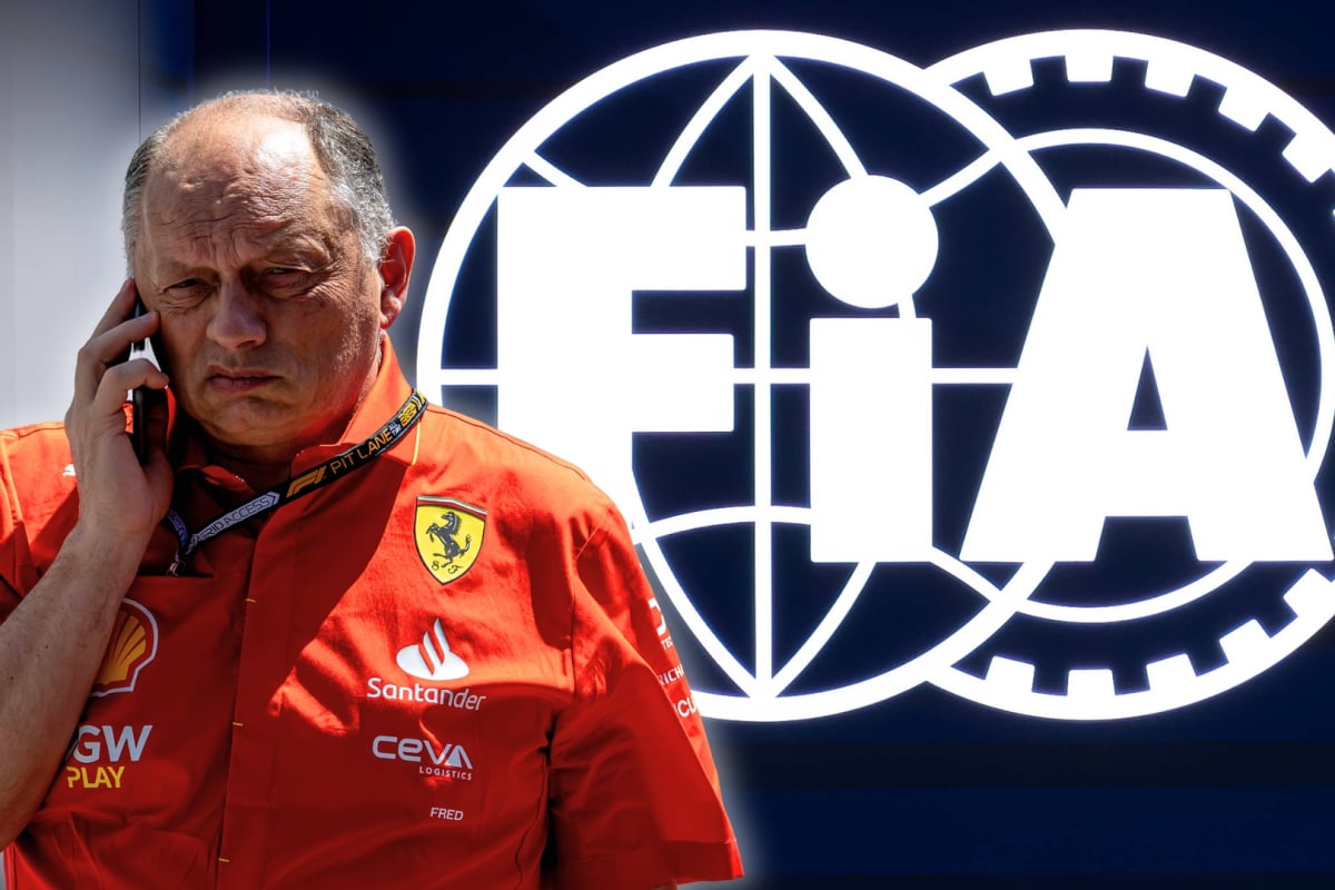 Vasseur on the phone in Ferrari shirt with background of dark blue and white FIA logo