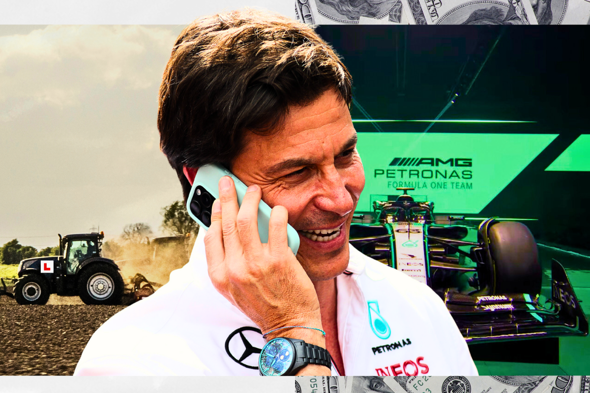 Toto Wolff poses with a phone with a background of a farm and a Mercedes F1 car