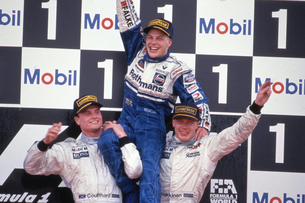 Mika Hakkinen and David Coulthard lift up Jacques Villeneuve after he becomes 1997 world champion