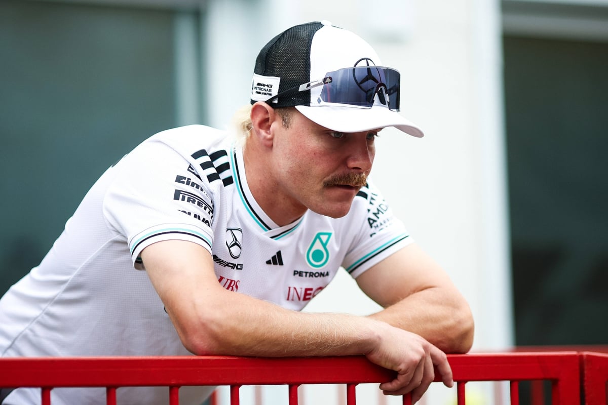 Bottas in an official Mercedes F1 team t-shirt, slumped over a railing in the F1 paddock looking despondent