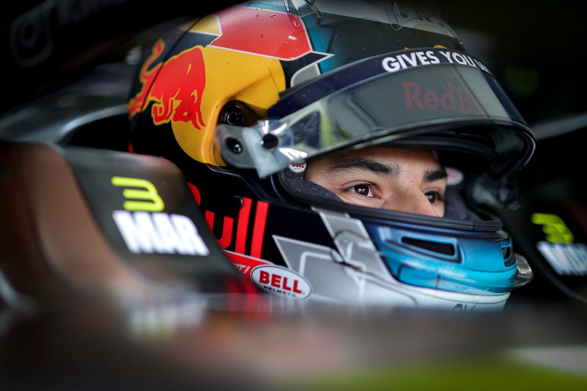 Pepe Marti sits in his Formula E car with his Red Bull-inspired helmet on