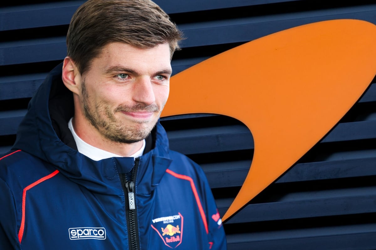 Max Verstappen grins in front of a McLaren logo background