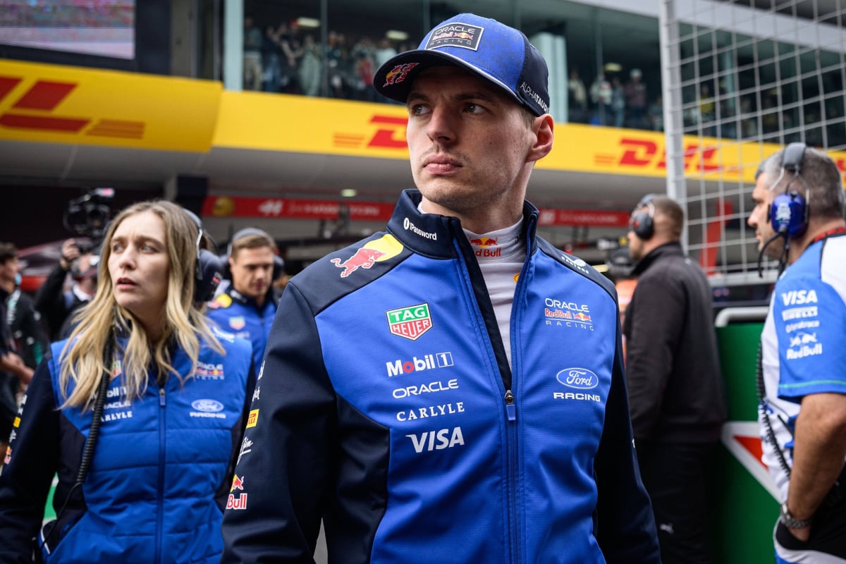 Verstappen walking on the F1 grid in Red Bull 2026 kit looking annoyed