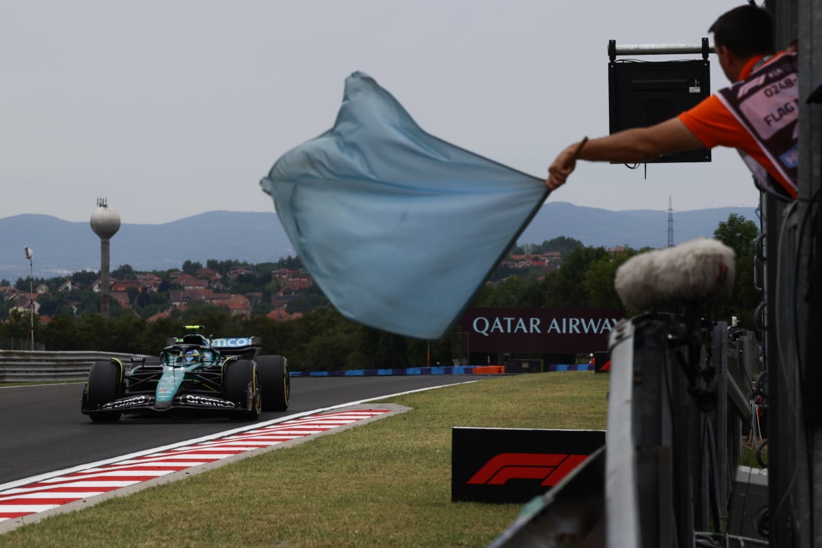 A marshall waves a blue flag at the 2024 Hungarian Grand Prix trackside