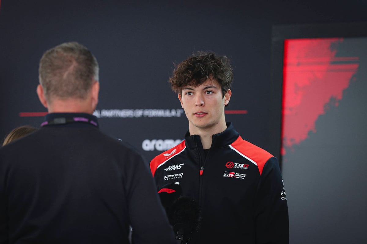 Oliver Bearman chats to a fellow team member at Haas