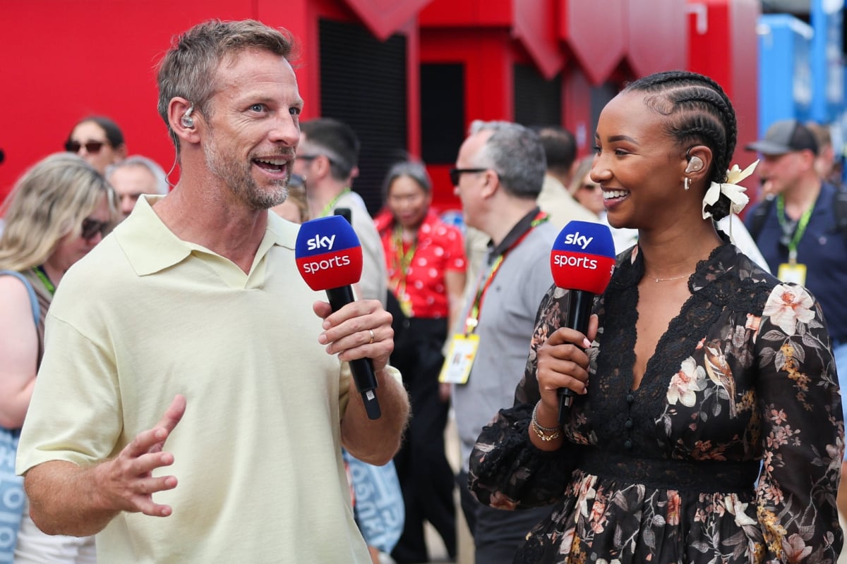 Jenson Button and Naomi Schiff hold Sky mics as they talk in the Silverstone paddock