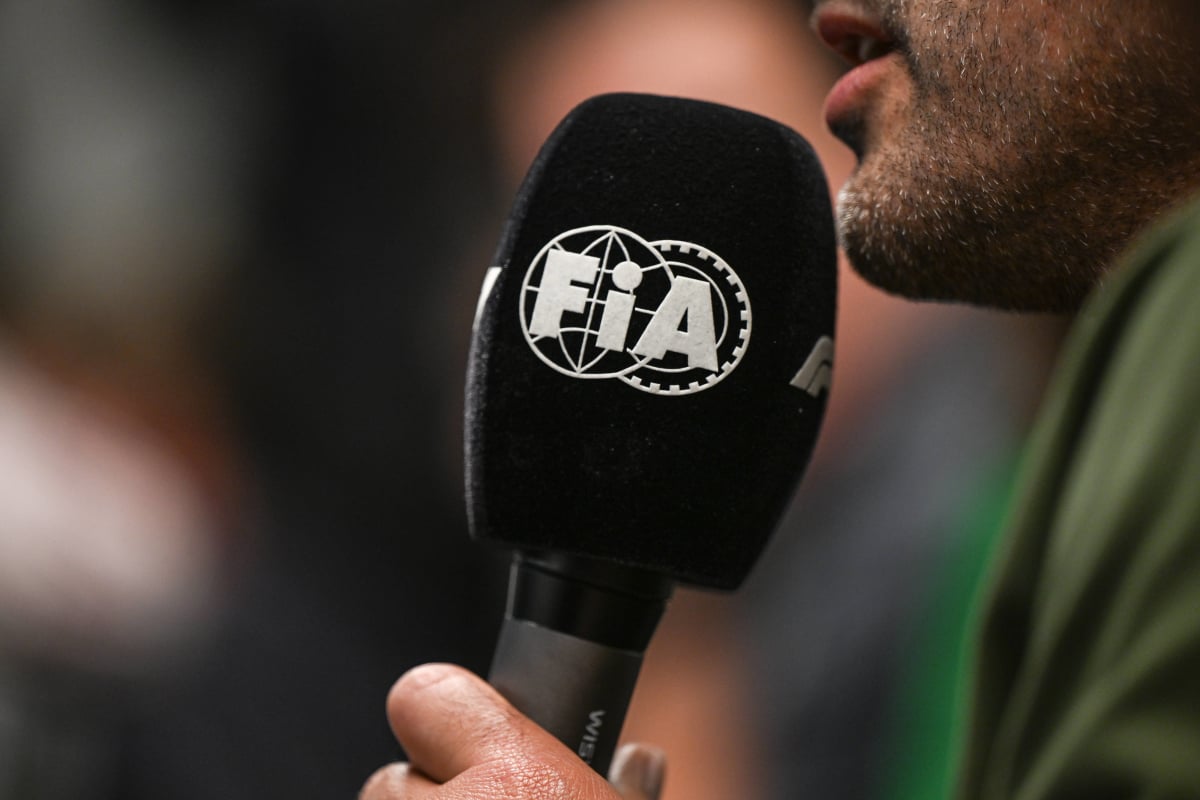 An interviewer holds an FIA microphone