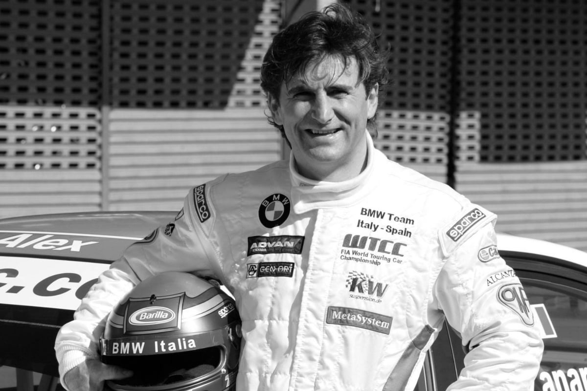 Alex Zanardi smiles at the camera, the photo is black and white