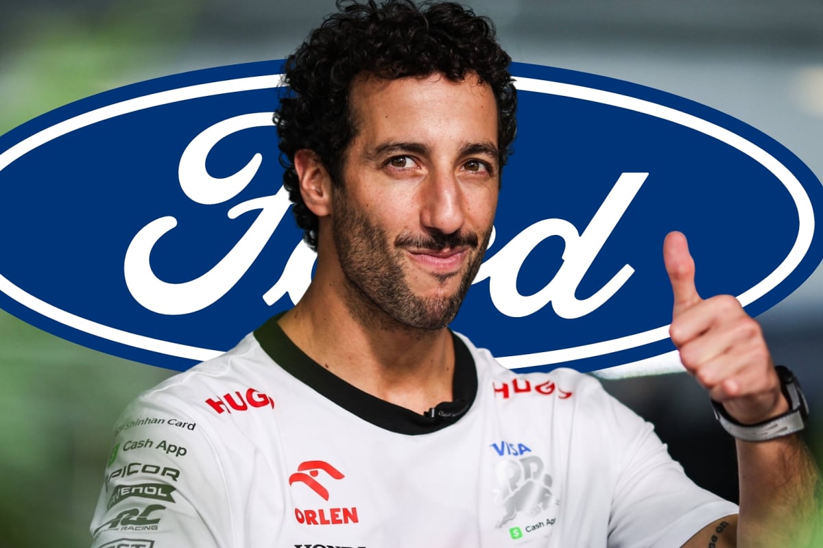 Daniel Ricciardo smiles and gives a thumbs up with the Ford logo in the background