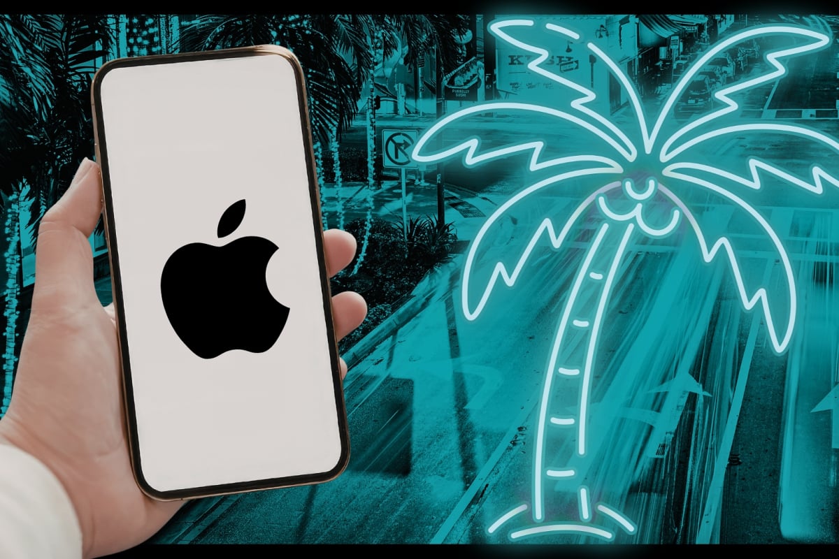 A hand holding an iPhone with the Apple logo amid a neon backdrop of a palm tree resembling Miami
