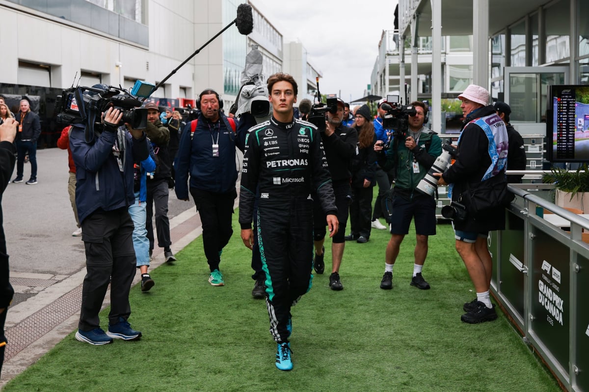 George Russell walks down the paddock surrounded by photographers after retiring from the Canadian Grand Prix