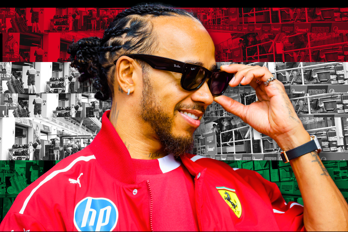 Hamilton in red Ferrari kit smiling, holding black sunglasses with red, white and green Hungarian flag