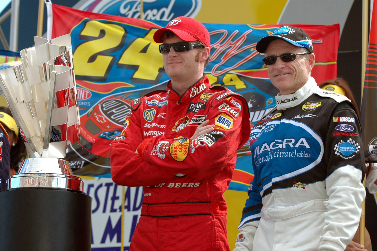 An image of NASCAR drivers Mark Martin and Dale Earnhardt Jr. standing next to the championship trophy