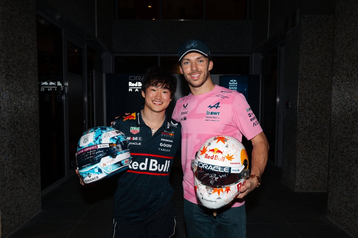 Yuki Tsunoda and Pierre Gasly smiling at the camera after their helmet swap at the Abu Dhabi Grand Prix 2025