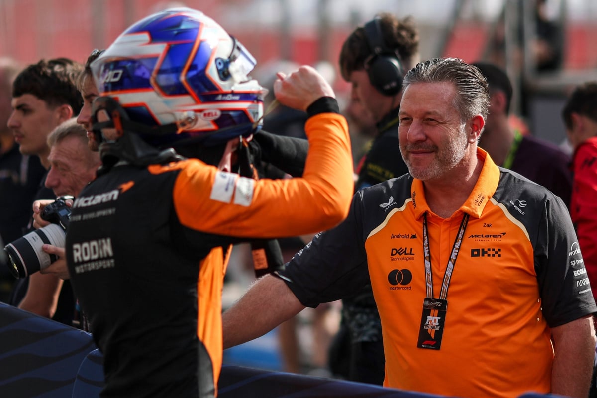 Dunne facing away from the camera towards McLaren boss Brown in the paddock