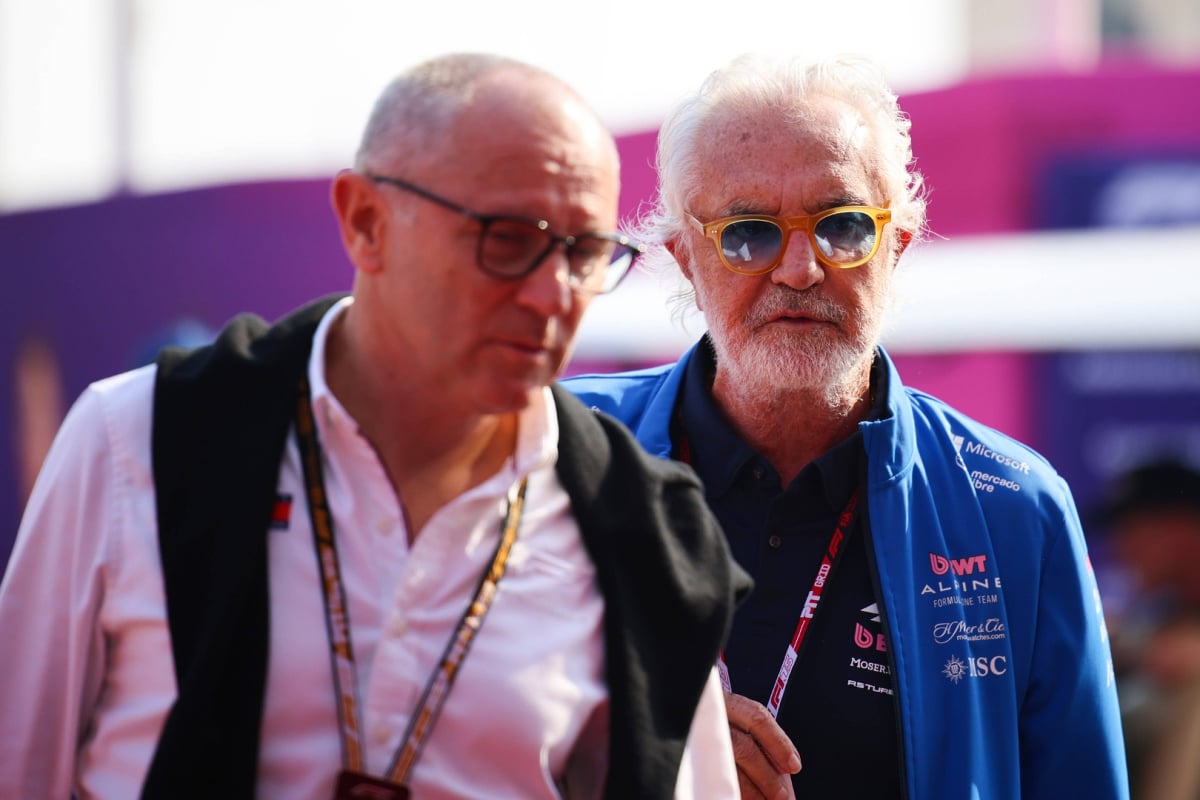 Domenicali closest to camera but out of focus in white shirt walking next to Briatore in blue and pink Alpine kit
