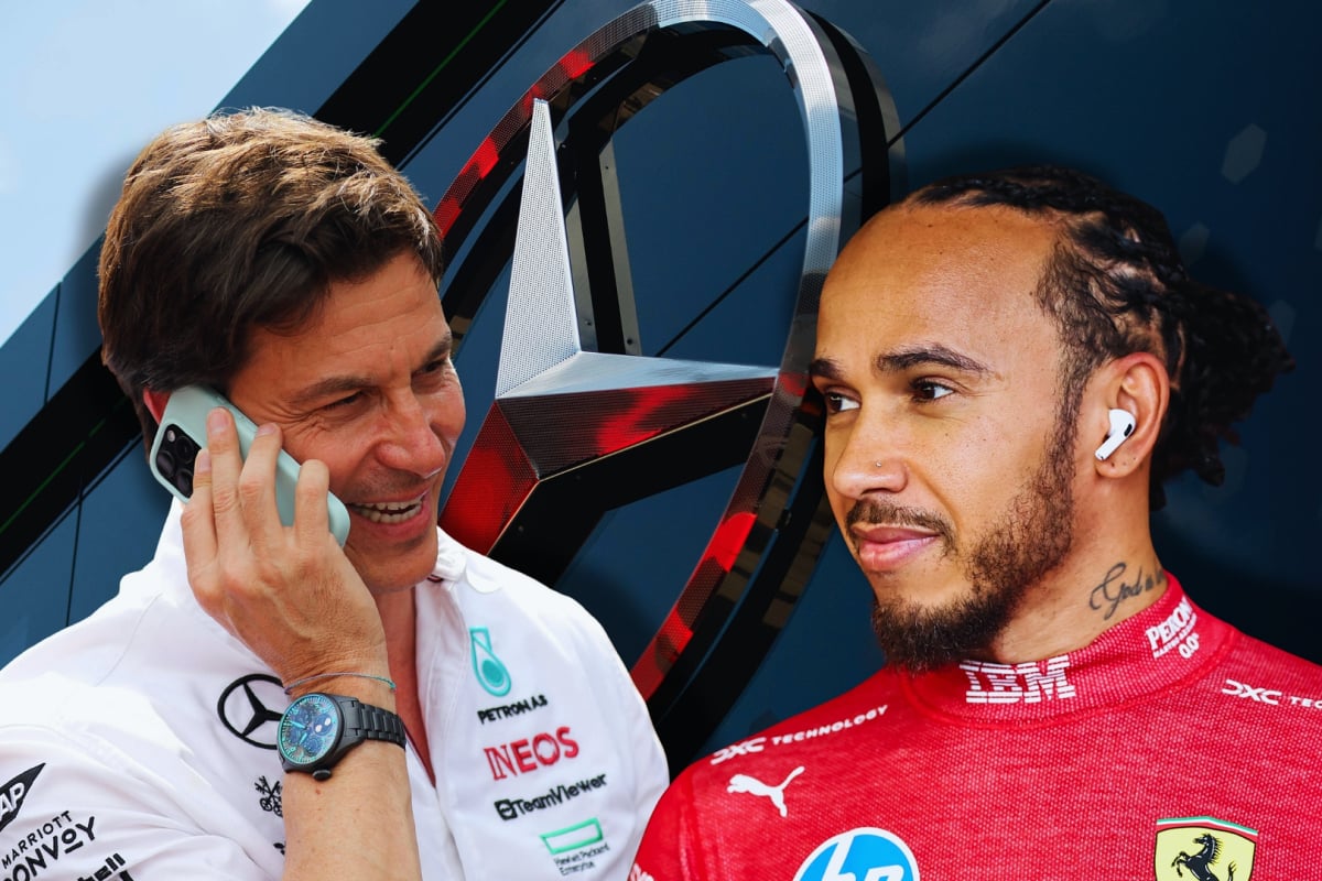 Toto Wolff laughing with Lewis Hamilton in front of Mercedes logo