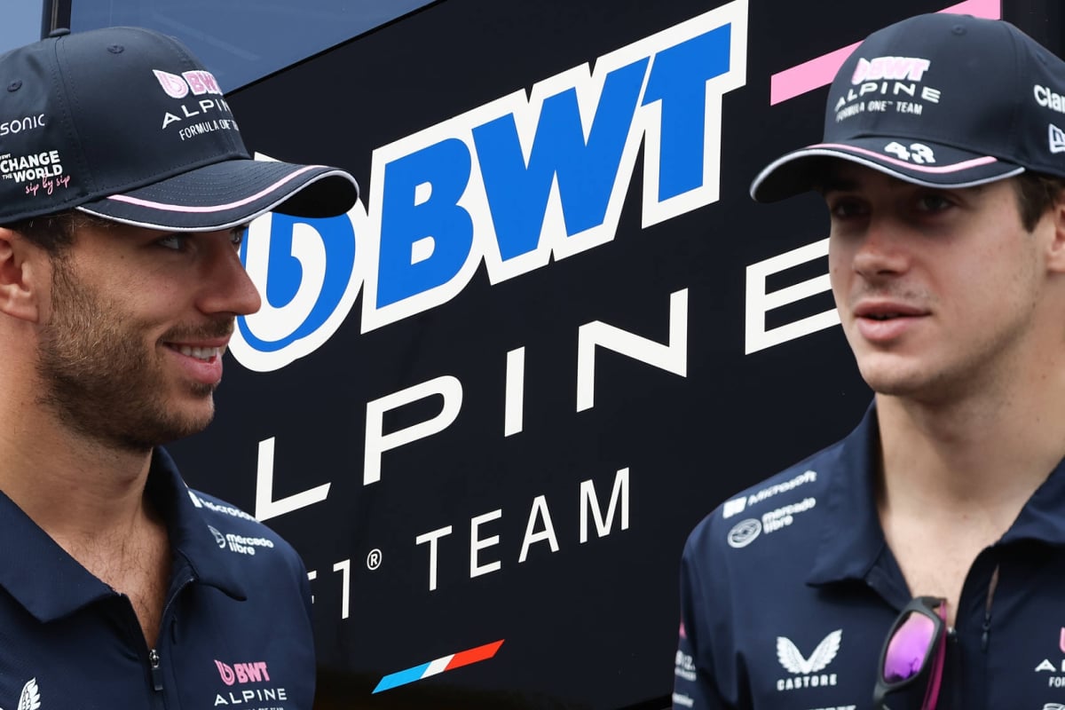 Pierre Gasly and Franco Colapinto look at each other to the background of an Alpine logo