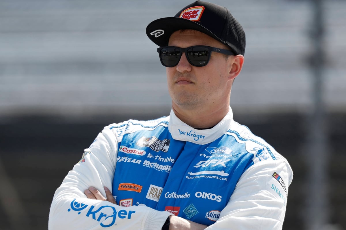 An image of RFK Racing NASCAR star Ryan Preece looking into the distance with his arms crossed