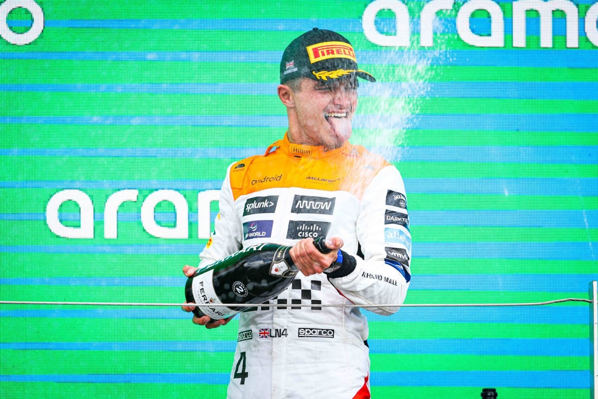 Lando Norris celebrates on the podium with his McLaren team