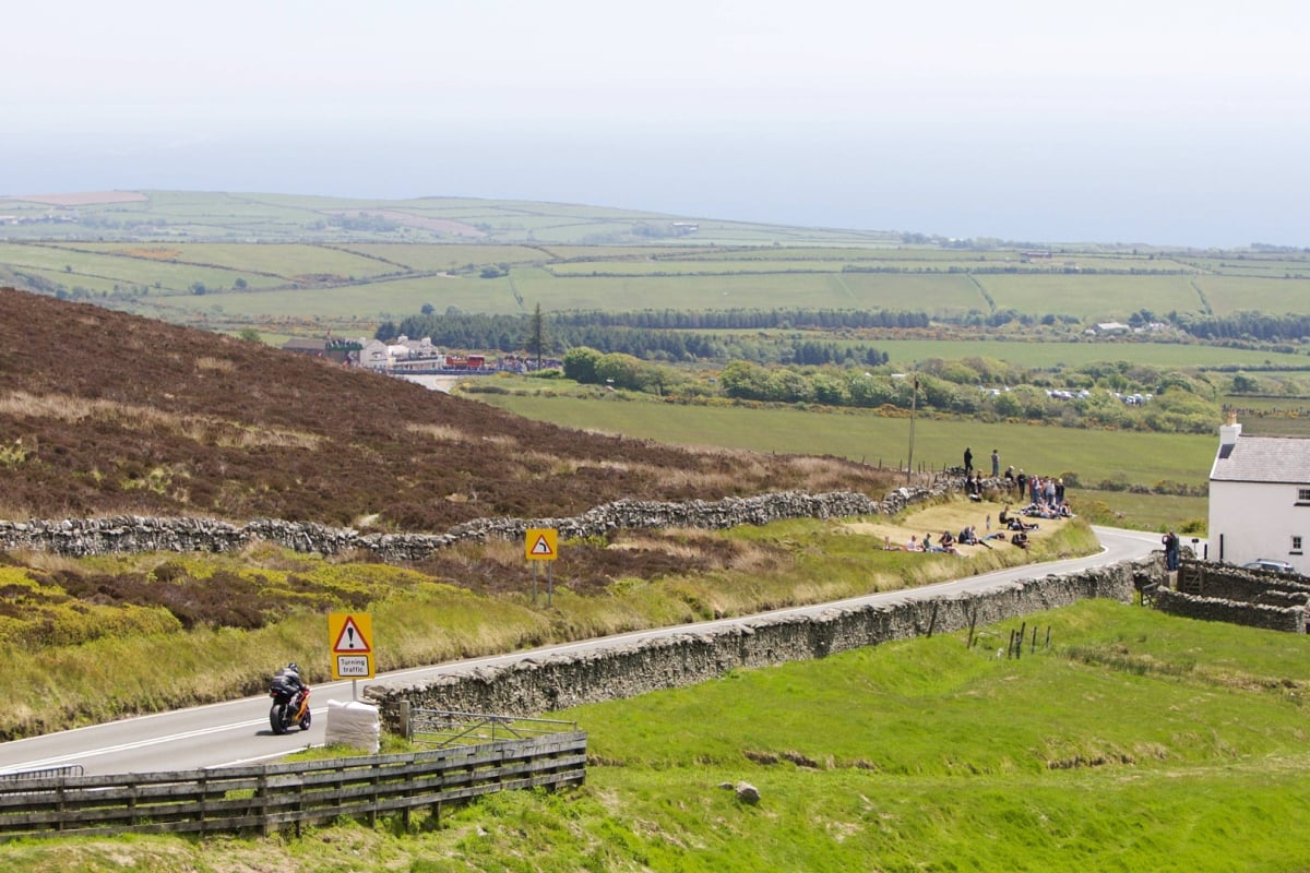Shot of the open roads at the Isle of Man TT Races with bikes and spectators in the distance
