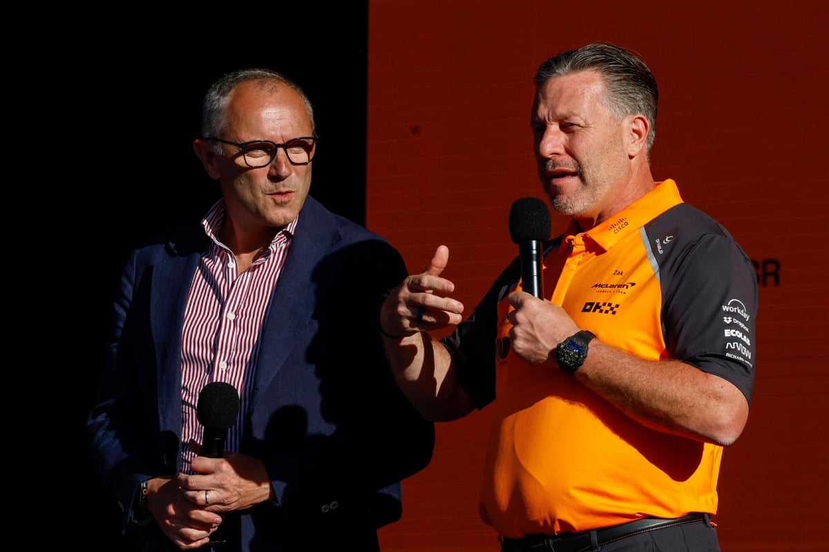 Domenicali in a suit stood next to Brown in McLaren F1 kit, both holding mics on stage at McLaren event in Trafalgar Square