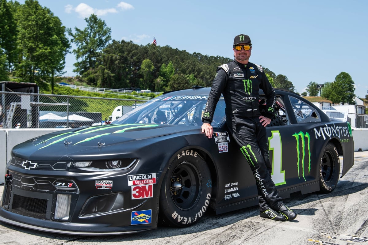 An image of NASCAR champion Kurt Busch with the car he's set to drive in the HSR NASCAR Classic