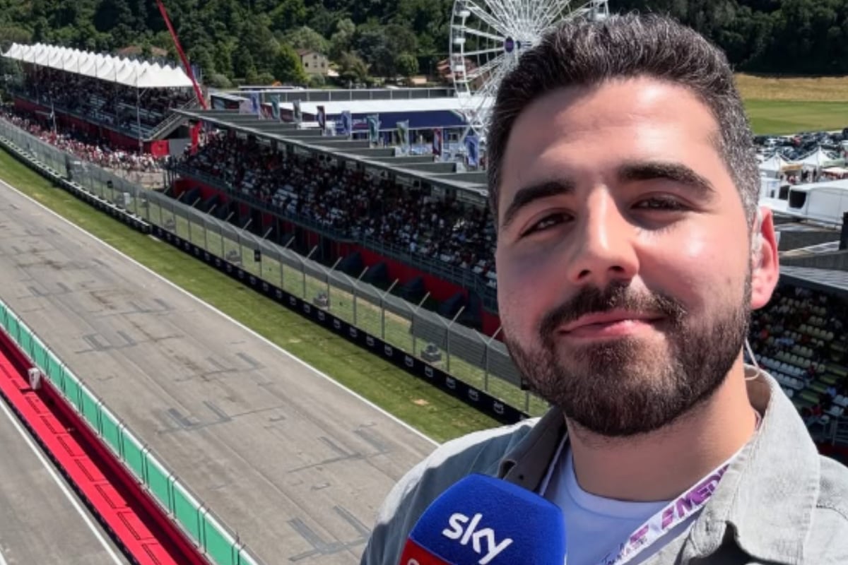 Harry Benjamin taking a selfie with a panoramic view of Imola and holding a Sky Sports microphone 