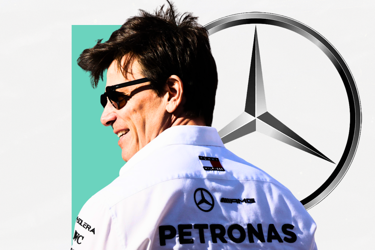 Wolff looking sideways and smiling with sunglasses on with Mercedes silver logo and white and turqouise block background