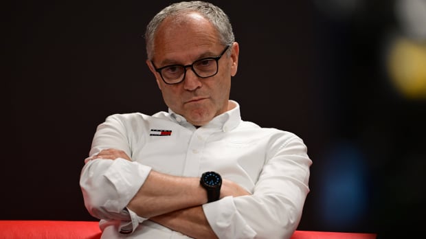 F1 president Domenicali sat with his arms crossed in a white shirt with Tommy Hilfiger logo, straight expression on his face — Foto: © IMAGO