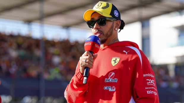 Hamilton in red Ferrari hoodie and yellow 2026 British GP cap holding Sky Sports F1 mic — Photo: © IMAGO