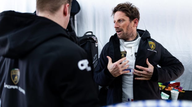 Romain Grosjean puts his jacket on in a motor garage — Photo: © IMAGO