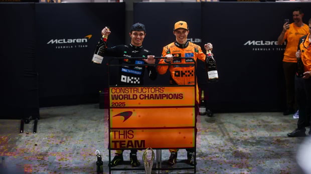 Norris and Piastri smiling in front of 'world champions' sign after the 2025 Singapore GP
