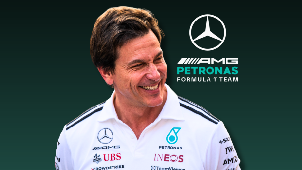 Wolff smiling in white Mercedes shirt with blue and black gradient background featuring F1 logo