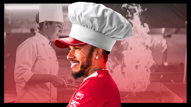 Lewis Hamilton smiling with a chef's hat on in full Ferrari gear, while chefs work tirelessly behind him with pans that have flames coming out from them