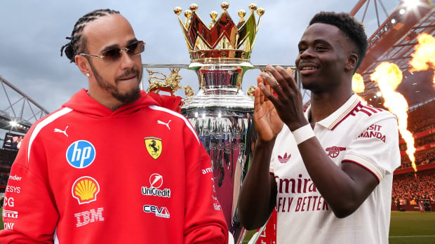 Lewis Hamilton looks over at a clapping Bukayo Saka in front of the Emirates Stadium with the Premier League trophy between them both — Photo: © IMAGO
