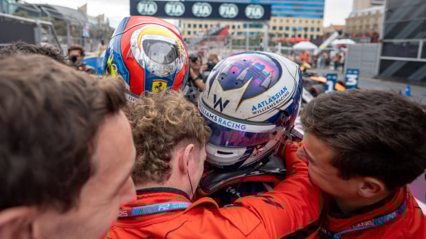 Williams junior Luke Browning wearing his race helmet and celebrating with his team after a race